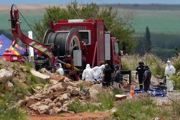 Forensic service workers carry body remains in blue body bags during a rescue operation to rescue miners from below ground in an abandoned gold mine in Stilfontein, South Africa, Wednesday, Jan. 15, 2025. (AP Photo/Themba Hadebe)