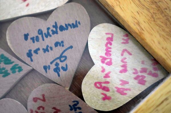 Pieces of heart-shaped wood with messages from friends of Sunma Piamboon and Danaya Phonphayung are kept in a wooden frame in Bangkok, Thailand, on Jan. 13, 2025. The words read "Wish you a lot of happiness." (AP Photo/Sakchai Lalit) I