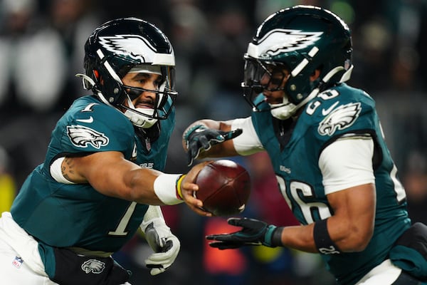 Philadelphia Eagles quarterback Jalen Hurts (1) hands the ball off to Philadelphia Eagles running back Saquon Barkley (26) during the first half of an NFL wild-card playoff football game against the Green Bay Packers on Sunday, Jan. 12, 2025, in Philadelphia. (AP Photo/Derik Hamilton)