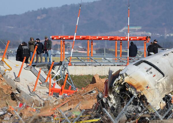 Experts from the U.S. National Transportation Safety Board (NTSB) and joint investigation team between the U.S. and South Korea check the site of a plane crash at Muan International Airport in Muan, South Korea, Tuesday, Dec. 31, 2024. (Son Hyung-joo/Yonhap via AP)