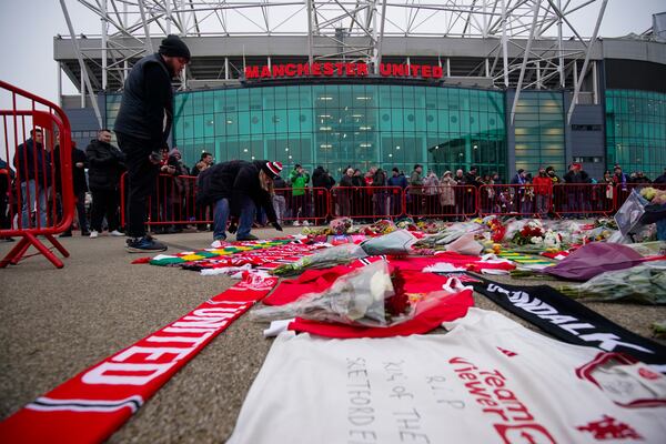 People lay flowers in memory of Denis Law prior the English Premier League soccer match between Manchester United and Brighton and Hove Albion, at the Old Trafford stadium in Manchester, England, Sunday, Jan. 19, 2025. (AP Photo/Dave Thompson)