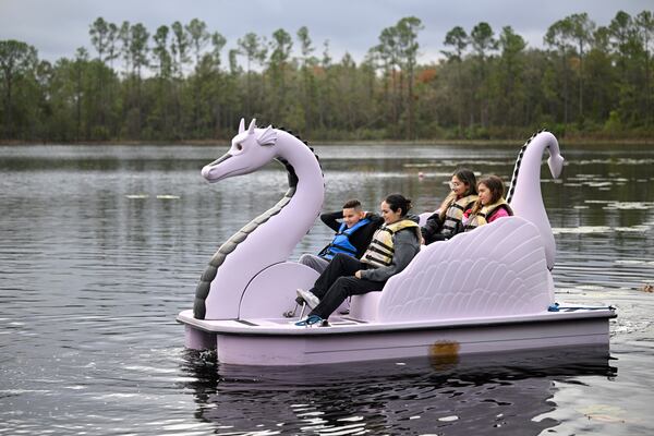 Volunteer counselors and children ride a paddle boat on Lake Palmer at Camp Boggy Creek, where children with serious illnesses and their families are provided with a free camp experience, Jan. 11, 2025, in Eustis, Fla. (AP Photo/Phelan M. Ebenhack)