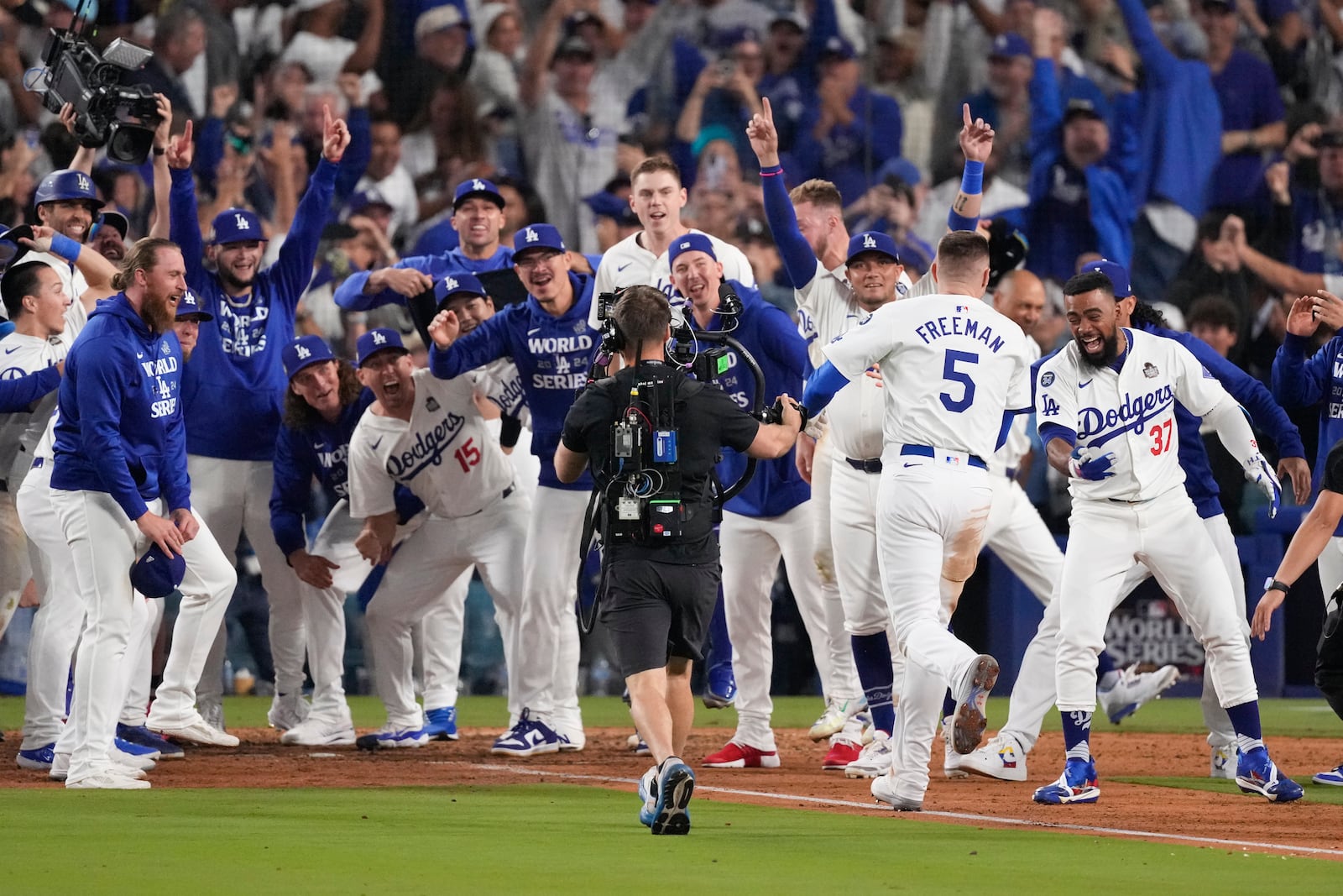 Los Angeles Dodgers' Freddie Freeman (5) is met at home plate after hitting a walk-off grand slam home run during the 10th inning in Game 1 of the baseball World Series against the New York Yankees, Friday, Oct. 25, 2024, in Los Angeles. (AP Photo/Mark J. Terrill)