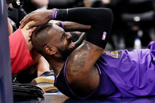 Los Angeles Lakers forward LeBron James winces after being hit in the head while shooting during the first half of an NBA basketball game against the Los Angeles Clippers, Sunday, Jan. 19, 2025, in Inglewood, Calif. (AP Photo/Mark J. Terrill)