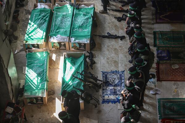 Masked militants from Hamas pray by the bodies of fifteen members of their fighters, who were killed in Israeli bombardment of the Gaza Strip, in Khan Younis, Friday, Jan. 31, 2025. (AP Photo/Jehad Alshrafi)