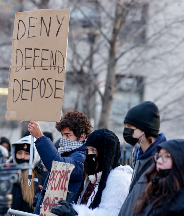 Demonstrators hold up signs while waiting for the arrival of Luigi Mangione for his arraignment in Manhattan Criminal Court, Monday, Dec. 23, 2024, in New York. (AP Photo/Stefan Jeremiah)