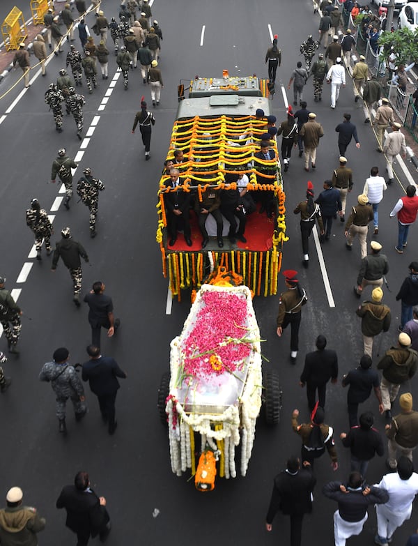 Security officials and others walk with the hearse carrying the body of former Indian Prime Minister Manmohan Singh towards the cremation site in New Delhi, India, Saturday, Dec. 28, 2024. (AP Photo)