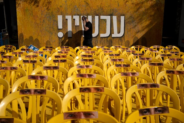 A display of yellow chairs representing hostages held in the Gaza Strip, and a banner reading "now!" in Hebrew, are seen in Tel Aviv, Israel, on the first day of a ceasefire between Israel and Hamas, as three hostages are set to be released from captivity, Sunday, Jan. 19, 2025. (AP Photo/Maya Alleruzzo)