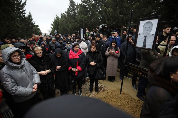 People stand at the grave of pilot in command Igor Kshnyakin during a funeral of the crew members of the Azerbaijan Airlines Embraer 190, killed in a deadly plane crash in Kazakhstan this week, at the II Alley of Honor in Baku, Azerbaijan, Sunday, Dec. 29, 2024. (AP photo)