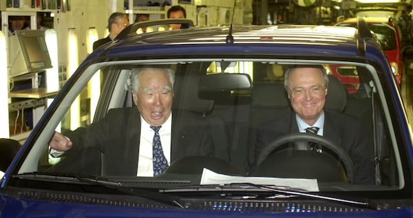 FILE - Osamu Suzuki, head of the Suzuki Motor Corporation, left, sits in the first Suzuki Ignis made in Hungary next to Hungarian Prime Minister Peter Medgyessy just after the production start of the new Suzuki model in Esztergom near Budapest, Hungary, April 10, 2003. (AP Photo/Bela Szandelszky, File)