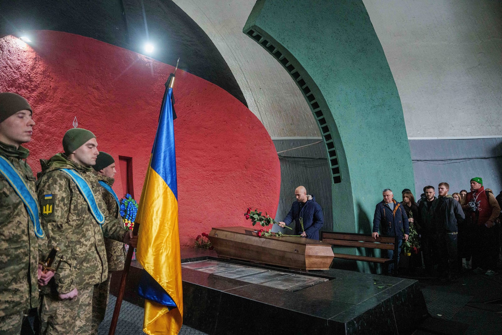 A man places flowers on the coffin of fallen Ukrainian serviceman of 3rd assault brigade Danylo Liashkevych, known as "Berserk", who was killed together with his girlfriend Valentyna Nagorna, known as "Valkiria", during the funeral ceremony at a crematorium in Kyiv, Ukraine, Friday Nov. 8, 2024. (AP Photo/Evgeniy Maloletka)