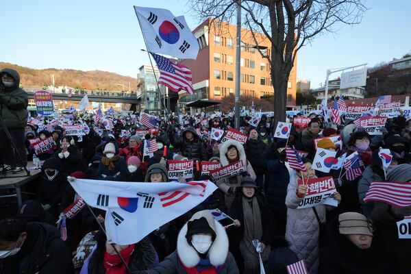 Supporters of impeached South Korean President Yoon Suk Yeol stage a rally to oppose a court having issued a warrant to detain Yoon, as police offices stand guard near the presidential residence in Seoul, South Korea, Friday, Jan. 3, 2025. The letters read "Oppose Impeachment." (AP Photo/Lee Jin-man)