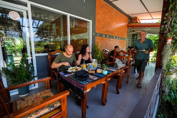 Neil Farmiloe, a New Zealander who owns the Kiwi Kitchen restaurant, serves food to the foreign tourist in Vang Vieng, Laos, Friday, Nov. 22, 2024. (AP Photo/Anupam Nath)