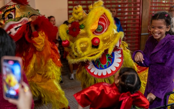 A performer dressed in a lion costume scares a girl as he dances the traditional Chinese Lion Dance at the start of Chinese Lunar New Year celebrations in Havana, Tuesday, Jan. 28, 2025. (AP Photo/Ramon Espinosa)