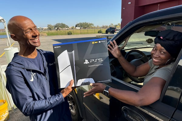 Pastor Antoine Barriere, left, hands a PlayStation 5 to Leticia Clanton after she handed over her handgun Tuesday, Dec. 31, 2024, in New Orleans. (AP Photo/Jack Brook)