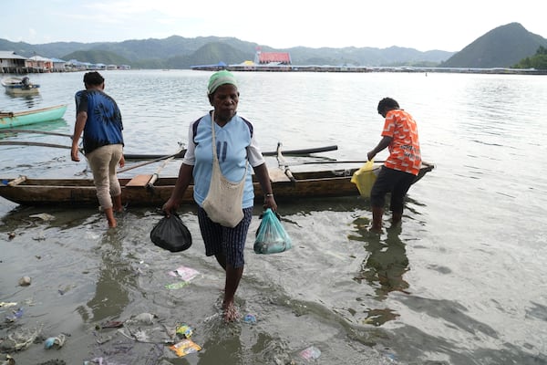 A woman carries fish in plastic bags to a market at Enggros village in Jayapura, Papua province, Indonesia on Wednesday, Oct. 2, 2024. (AP Photo/Firdia Lisnawati)