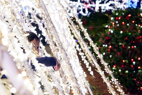 A child pokes their head through a light display at the Lights of Joy display Monday, Dec. 16, 2024, in Kennesaw, Ga. (AP Photo/Brynn Anderson)