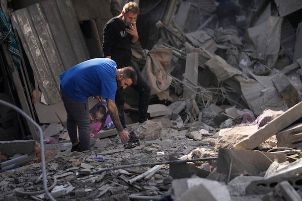 Two men stand at the site of an Israeli airstrike that hit central Beirut, Lebanon, Saturday, Nov. 23, 2024. (AP Photo/Hussein Malla)