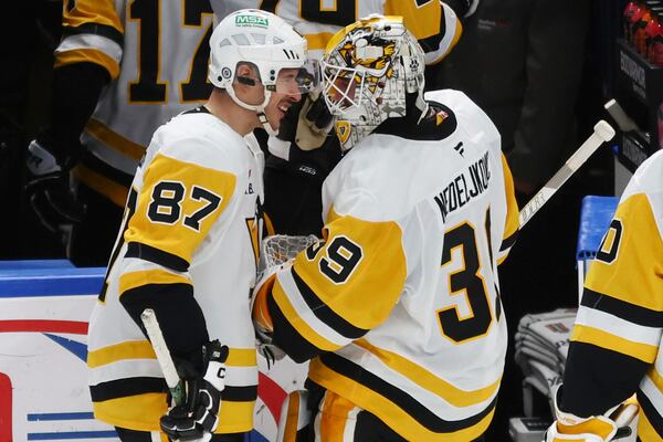 Pittsburgh Penguins goaltender Alex Nedeljkovic (39) and center Sidney Crosby (87) celebrate a 5-2 victory following the third period of an NHL hockey game against the Buffalo Sabres Friday, Jan. 17, 2025, in Buffalo, N.Y. (AP Photo/Jeffrey T. Barnes)