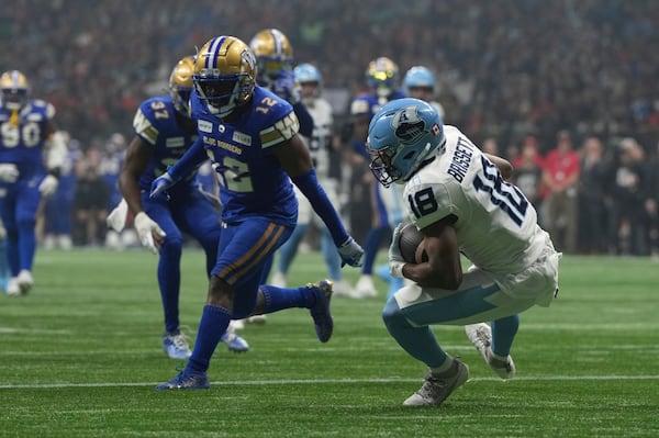 Toronto Argonauts' Dejon Brissett (18) scores a touchdown as Winnipeg Blue Bombers' Nick Taylor (12) looks on during the second half of a CFL football game at the 111th Grey Cup in Vancouver, British Columbia, Sunday, Nov. 17, 2024. (Ethan Cairns/The Canadian Press via AP)