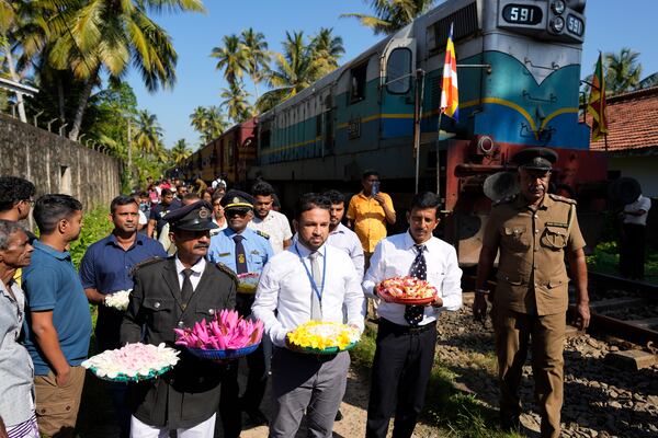 Railway workers and locomotive drivers carry flowers to offer at a memorial built in memory of those who died during 2004 Indian Ocean tsunami as they mark the 20th anniversary in Peraliya, Sri Lanka, Thursday, Dec. 26, 2024. (AP Photo/Eranga Jayawardena)