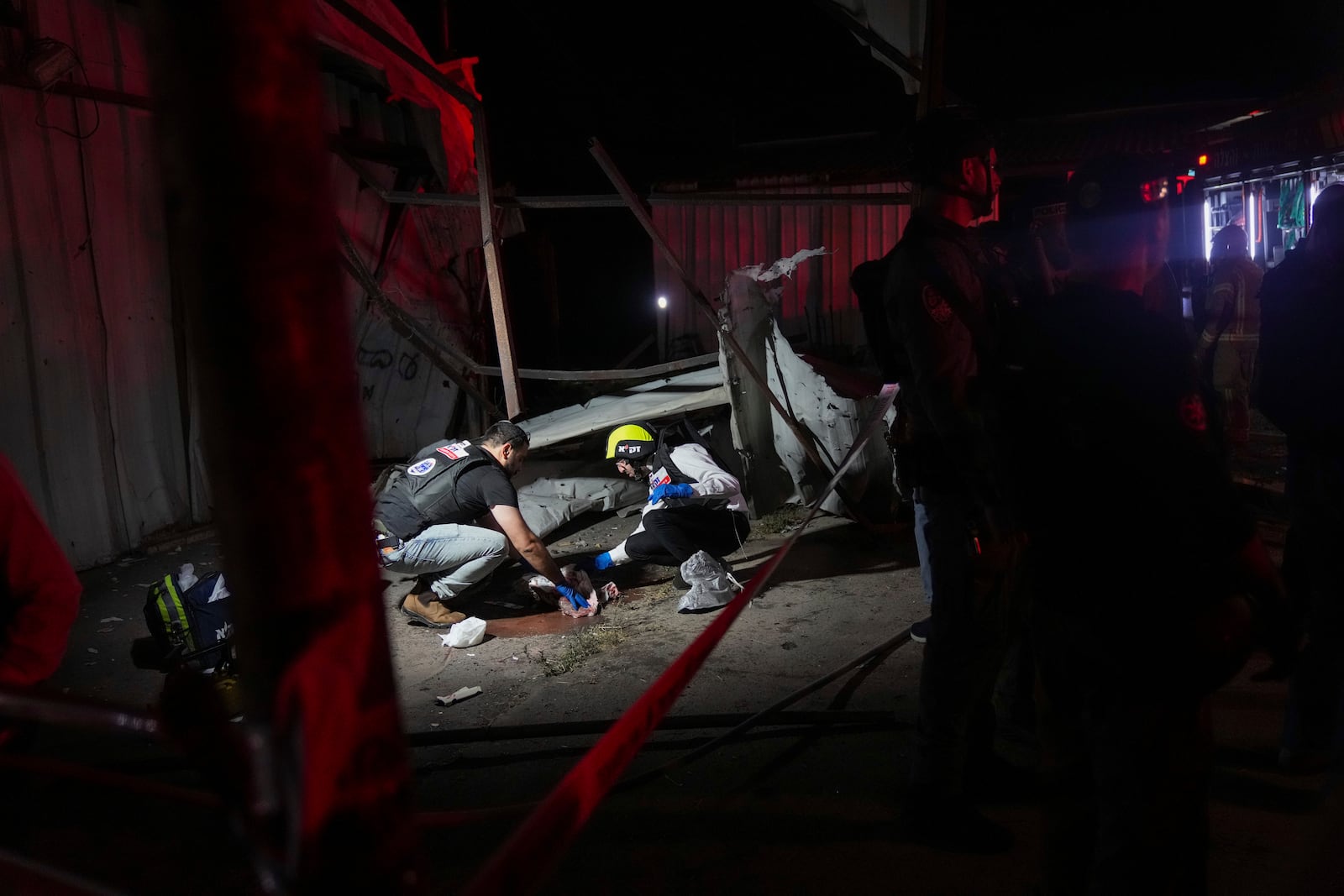 Members of ZAKA rescue services clean the blood stains at the site where a rocket fired from Lebanon hit a storage facility in the northern Israeli town of Nahariya, killing two people on Tuesday, Nov. 12, 2024. (AP Photo/Francisco Seco)