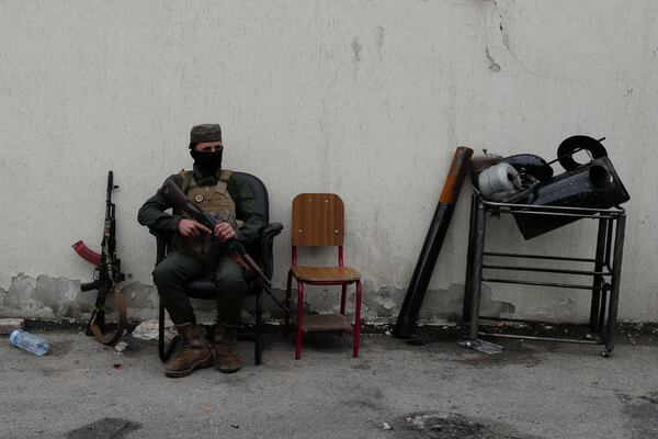 A member of the security forces of the newly formed Syrian government looks on as members of Bashar Assad's army, or a pro-government militia, line up to register as part of an "identification and reconciliation" process in Damascus, Syria, Monday, Dec. 30, 2024. (AP Photo/Omar Sanadiki)