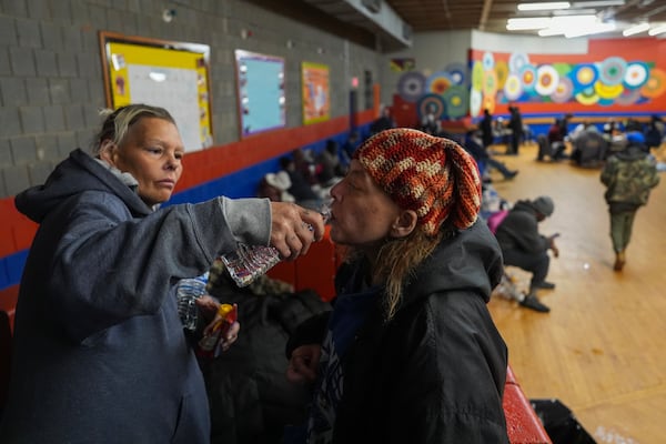 Harley Moody, right, who is blind, takes a sip of water, as Angel Rodda, left, holds it for her after they arrived inside a daytime warming shelter, Tuesday, Jan. 7, 2025, in Cincinnati. (AP Photo/Joshua A. Bickel)