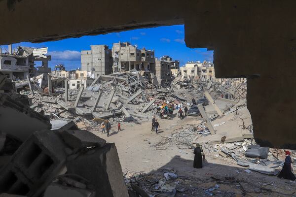 Palestinians walk through the rubble caused by the Israeli air and ground offensive in Rafah, southern Gaza Strip, Monday, Jan. 20, 2025. (AP Photo/Mariam Dagga)