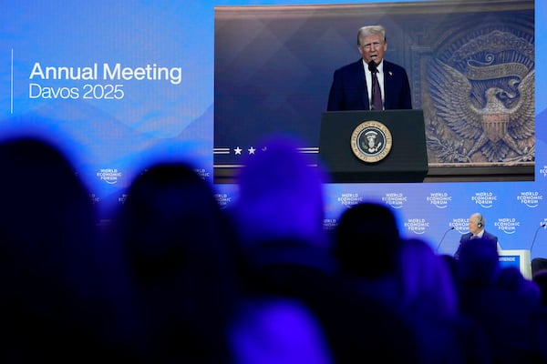 People follow a virtual speech of U.S. president Donald Trump at the Annual Meeting of World Economic Forum in Davos, Switzerland, Thursday, Jan. 23, 2025. (AP Photo/Markus Schreiber)