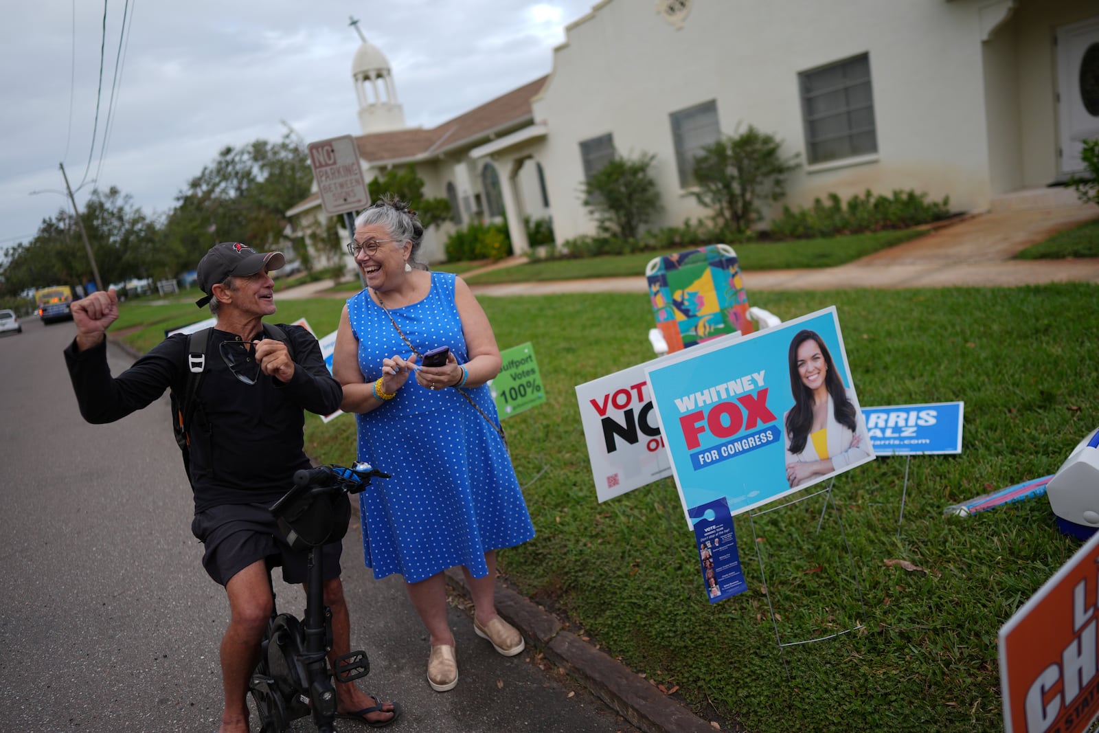 Trump supporter Barney Morin, left, cheers as Democratic poll greeter Lynn Akin helps him find his polling place so he can vote, outside a voting bureau at First United Methodist Church on Election Day, Tuesday, Nov. 5, 2024, in Gulfport, Fla. (AP Photo/Rebecca Blackwell)