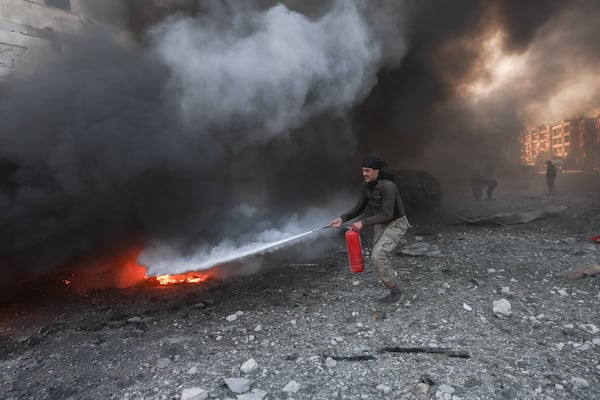 A man tries to put out the fire caused by an airstrike with a fire extinguisher outside a hospital complex in Idlib, Syria, Monday Dec.2, 2024.(AP Photo/Ghaith Alsayed)