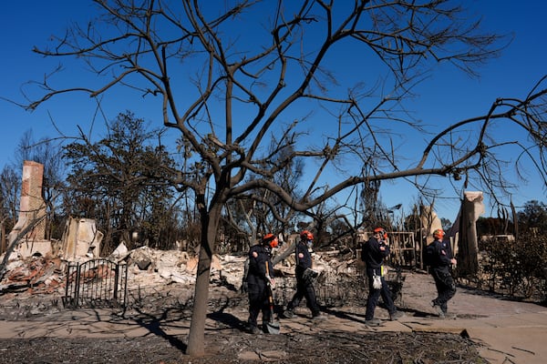 Members of a San Bernardino County Fire Department Search and Rescue crew work among the ruins of the Palisades Fire in the Pacific Palisades neighborhood of Los Angeles, Tuesday, Jan. 14, 2025. (AP Photo/Carolyn Kaster)