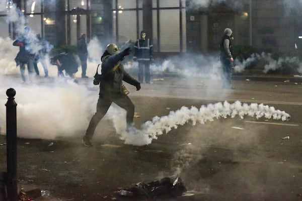 A demonstrator throws an object toward police as police block a street to prevent protesters rallying against the government's decision to suspend negotiations on joining the European Union for four years, outside the parliament's building in Tbilisi, Georgia, early Sunday, Dec. 1, 2024. (AP Photo/Zurab Tsertsvadze)