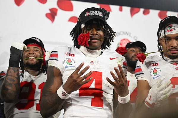 Ohio State wide receiver Jeremiah Smith (4) holds a rose in his mouth as he celebrates after the quarterfinals of the Rose Bowl College Football Playoff against Oregon, Wednesday, Jan. 1, 2025, in Pasadena, Calif. (AP Photo/Kyusung Gong)