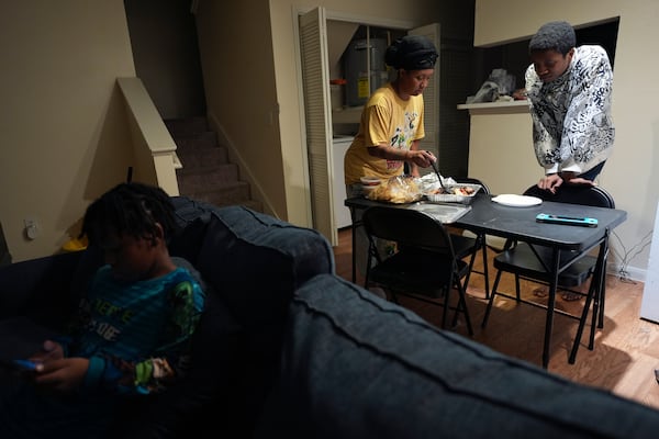 TiAnna Yeldell, center, with her sons Marq'ue, right, and Ivan, left, sets out dinner at her home, Thursday, Nov. 14, 2024, in Missouri City, Texas. (AP Photo/Eric Gay)