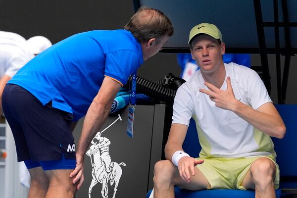 Jannik Sinner of Italy gestures as he talks with medical staff during his fourth round match against Holger Rune of Denmark at the Australian Open tennis championship in Melbourne, Australia, Monday, Jan. 20, 2025. (AP Photo/Asanka Brendon Ratnayake)