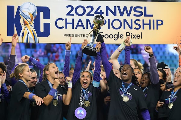 Orlando Pride forwards Marta, center, and Barbra Banda, right, lift the NWSL championship trophy together after defeating the Washington Spirit in an NWSL soccer game, Saturday, Nov. 23, 2024, in Kansas City, Mo. (AP Photo/Reed Hoffmann)