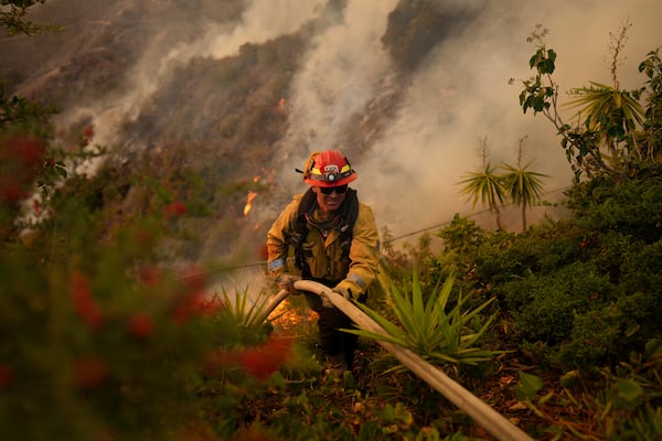 A firefighter sets up a hose while fighting the Palisades Fire in Mandeville Canyon Saturday, Jan. 11, 2025, in Los Angeles. (AP Photo/Eric Thayer)