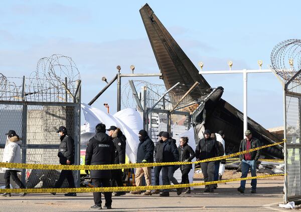 Experts from the U.S. National Transportation Safety Board (NTSB) and representatives from aircraft manufacturer Boeing Co. investigate the site of a plane crash at Muan International Airport in Muan, South Korea, Tuesday, Dec. 31, 2024. (Kim Sung-min/Yonhap via AP)