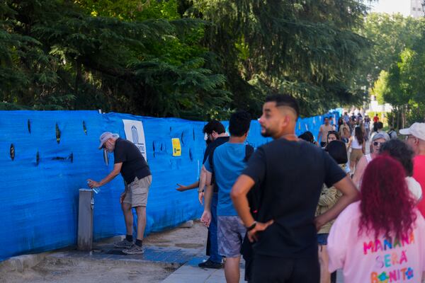 FILE - People queue to fill their water bottles up from a public drinking tap in Madrid, Spain, July 19, 2024. (AP Photo/Paul White, File)