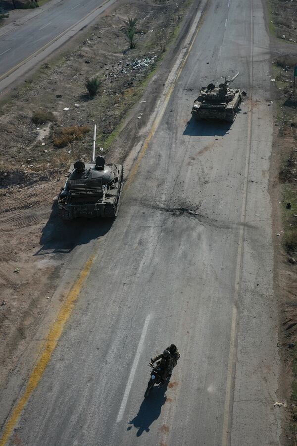 Syrian insurgents ride on motorcycles through abandoned Syrian army vehicles on a road in the outskirts of Hama, Syria, Tuesday Dec. 3, 2024.(AP Photo/Ghaith Alsayed)