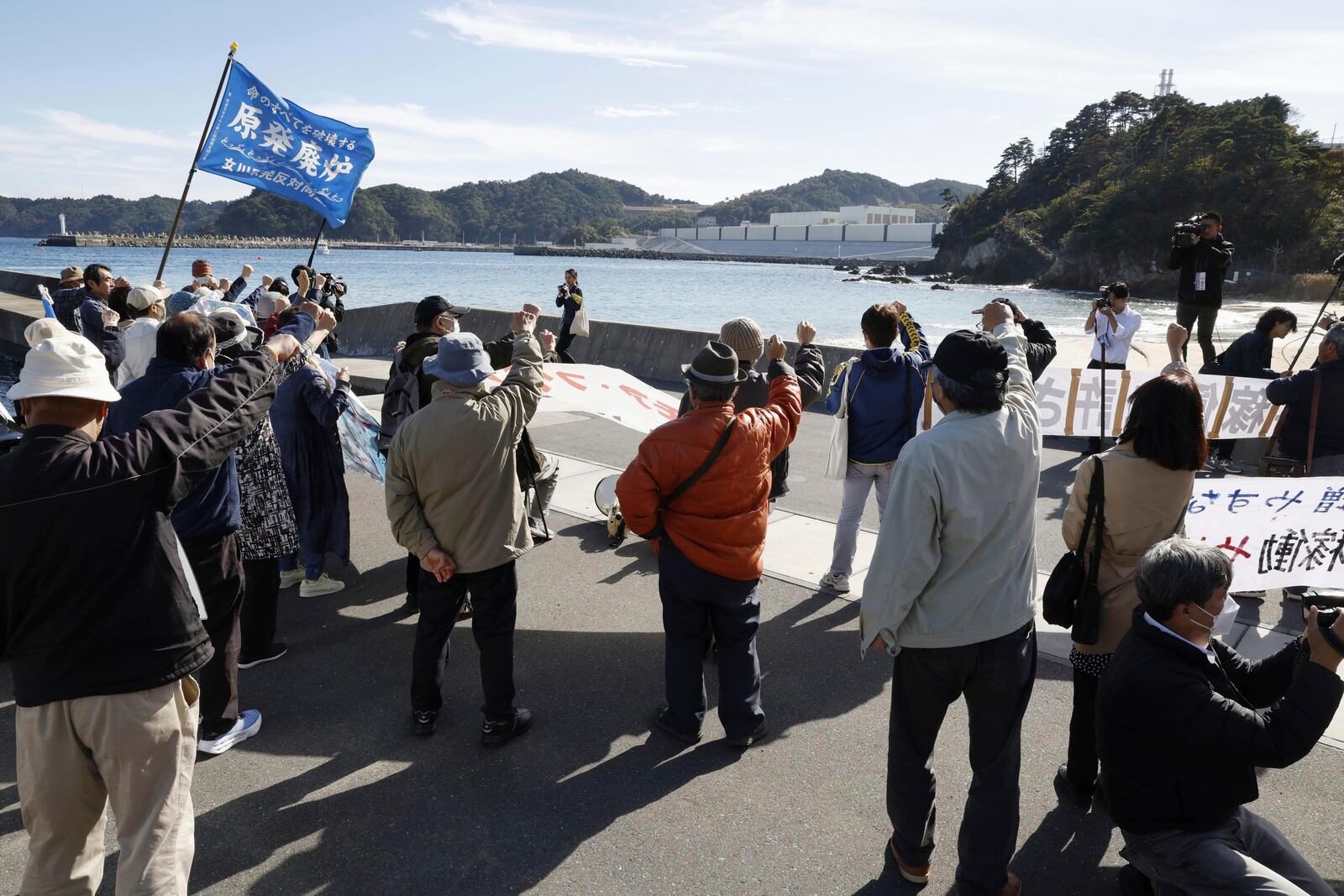 People protest against resuming operations of the Onagawa nuclear power plant, background, in Onagawa town, northeastern Japan, Tuesday, Oct. 29, 2024. (Miyuki Saito/Kyodo News via AP)