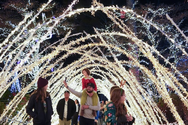 A family walks through a light display at the Lights of Joy display Monday, Dec. 16, 2024, in Kennesaw, Ga. (AP Photo/Brynn Anderson)