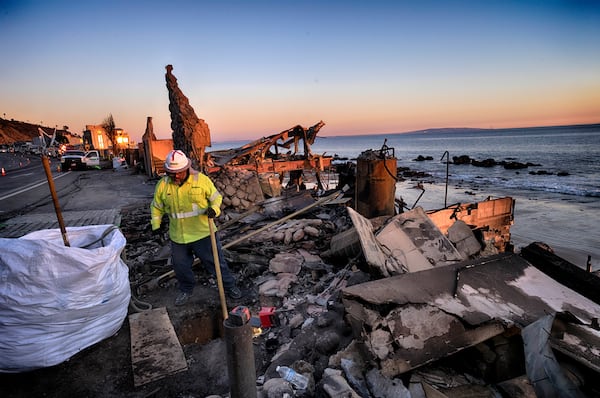 A crew for Southern California Edison prepares the ground for electric poles along the Pacific Coast Highway near homes destroyed from the Pacific Palisades Fire in Malibu, Calif., Wednesday. Jan. 15, 2025. (AP Photo/Richard Vogel)