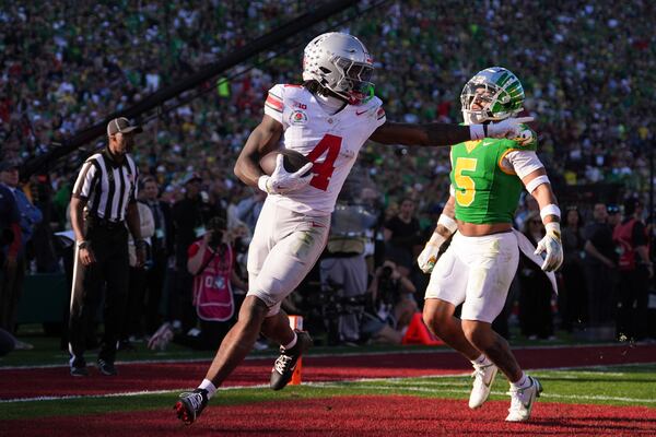 Ohio State wide receiver Jeremiah Smith (4) gestures as he scores a touchdown against Oregon defensive back Kobe Savage (5) during the first half in the quarterfinals of the Rose Bowl College Football Playoff, Wednesday, Jan. 1, 2025, in Pasadena, Calif. (AP Photo/Mark J. Terrill)