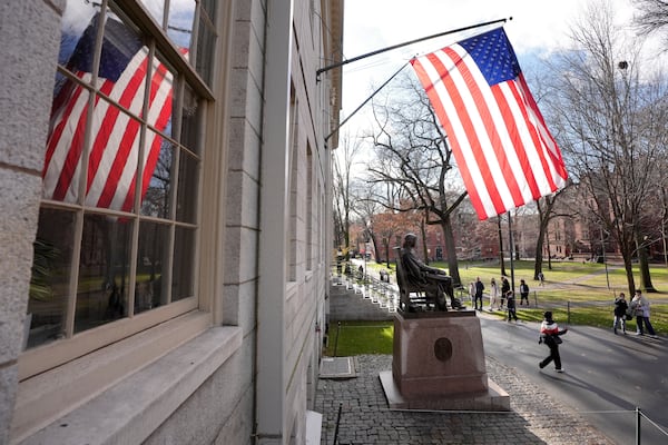 People walk past the John Harvard statue in Harvard Yard, Tuesday, Dec. 17, 2024, on the campus of Harvard University in Cambridge, Mass. (AP Photo/Steven Senne)