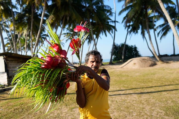 A man carries flowers to offer at a memorial built in memory of those who died during 2004 Indian Ocean tsunami, on the 20th anniversary of the calamity in Peraliya, Sri Lanka, Thursday, Dec. 26, 2024. (AP Photo/Eranga Jayawardena)