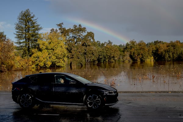 A rainbow is seen as a vehicle drives past a flooded vineyard after a major storm in Forestville, Calif., Saturday, Nov. 23, 2024. (Stephen Lam/San Francisco Chronicle via AP)