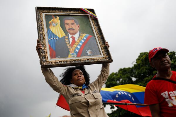 A member of the Bolivarian Militia holds up a painting depicting President Nicolas Maduro during a rally celebrating Maduro's July 28 reelection, in Caracas, Venezuela, Saturday, Sept. 28, 2024. (AP Photo/Cristian Hernandez)